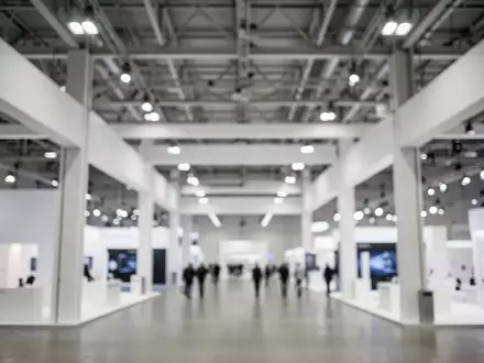 Heller, moderner Innenbereich einer Messehalle mit minimalistischer Architektur und industrieller Beleuchtung. - Foto: über boerse-global.de