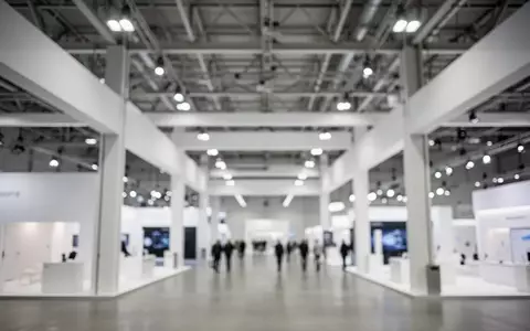 Heller, moderner Innenbereich einer Messehalle mit minimalistischer Architektur und industrieller Beleuchtung. - Foto: über boerse-global.de