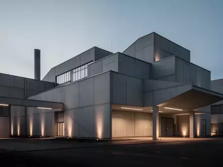 Moderne, minimalistische Industriefassade in Sachsen bei Dämmerung, die die Atmosphäre einer Arbeitsumgebung einfängt. - Foto: über boerse-global.de