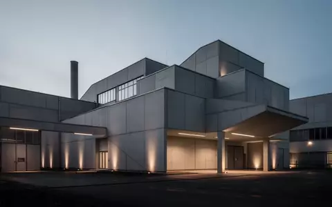 Moderne, minimalistische Industriefassade in Sachsen bei Dämmerung, die die Atmosphäre einer Arbeitsumgebung einfängt. - Foto: über boerse-global.de