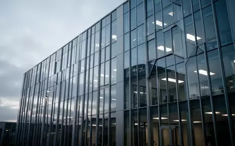 Modernes Bürogebäude bei bewölktem Himmel als Symbol für IT-Infrastruktur und Software-Herausforderungen. - Foto: über boerse-global.de