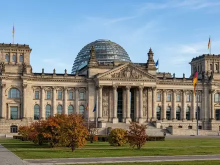 Das Berliner Reichstagsgebäude bei Tageslicht, fokussiert auf die architektonische Fassade und die Glaskuppel. - Foto: über boerse-global.de