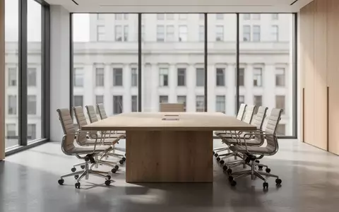 Ein minimalistischer Konferenzraum mit Holztisch und leeren Stühlen in einer modernen Büroumgebung. - Foto: über boerse-global.de
