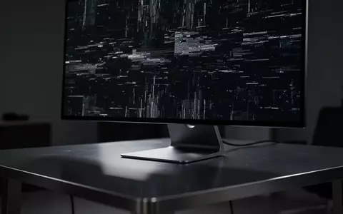 Ein dunkler, moderner Arbeitsplatz mit einem Monitor, der ein digitales Störungsmuster zeigt, symbolisch für Cyberkriminalität. - Foto: über boerse-global.de