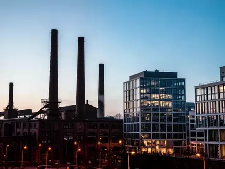 Industriegebiet in Mannheim bei Dämmerung mit Fabrikschornsteinen und moderner Architektur vor blauem Abendhimmel. - Foto: über boerse-global.de