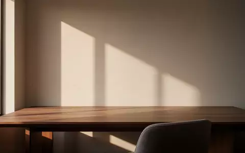 Ein minimalistischer, moderner Arbeitsplatz mit einem leeren Holztisch in hellem Morgenlicht. - Foto: über boerse-global.de