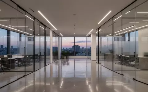 Modernes, minimalistisches Büro-Interieur mit Glaswänden und indirekter Beleuchtung in der Abenddämmerung. - Foto: über boerse-global.de