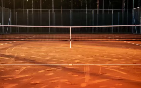 Ein leerer Tennisplatz aus rotem Sand in der Abendsonne, der auf ein professionelles Training in einer ruhigen Umgebung hindeutet. - Foto: über boerse-global.de