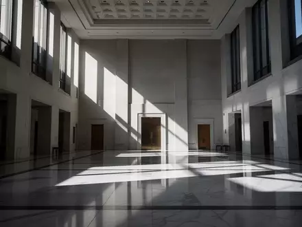 Ein minimalistisches, modernes Regierungsgebäude mit architektonischen Licht- und Schattenmustern auf dem Boden. - Foto: über boerse-global.de