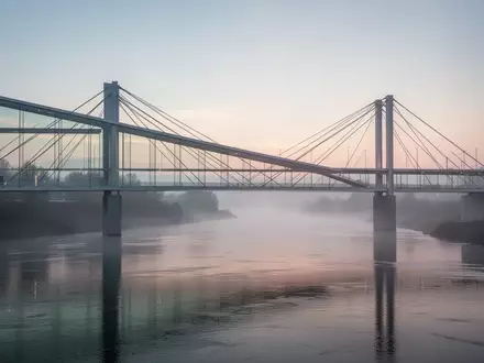 Eine moderne Brücke über einen Fluss im Morgengrauen als Symbol für grenzüberschreitende Zusammenarbeit. - Foto: über boerse-global.de