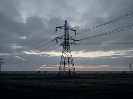 Hochspannungsmast in einer weiten, leeren Landschaft bei Dämmerung unter einem bedeckten Himmel. - Foto: über boerse-global.de