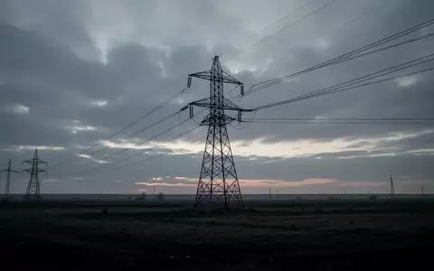 Hochspannungsmast in einer weiten, leeren Landschaft bei Dämmerung unter einem bedeckten Himmel. - Foto: über boerse-global.de