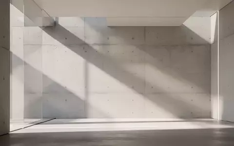 Ein minimalistischer, sonnendurchfluteter Innenraum mit geometrischen Linien und weichen Schatten an einer Betonwand. - Foto: über boerse-global.de