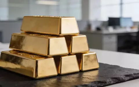 Nahaufnahme glänzender Goldbarren auf einer dunklen Schieferoberfläche bei natürlichem Licht. - Foto: über boerse-global.de