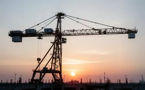 Ein moderner Industriekran vor einem Sonnenaufgang als Symbol für wirtschaftliche Investitionen und Infrastruktur. - Foto: über boerse-global.de