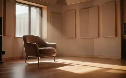 Ein minimalistisch eingerichteter Aufnahmeraum mit akustischen Wandpaneelen und einem leeren Sessel in ruhigem, natürlichem Licht. - Foto: über boerse-global.de