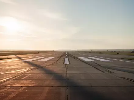 Eine weitläufige, leere Landebahn auf einem Flugplatz während der Dämmerung unter einem weiten Himmel. - Foto: über boerse-global.de