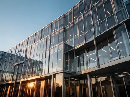 Moderne Glas- und Stahlfassade eines Bürogebäudes in der Schweiz bei goldenem Licht. - Foto: über boerse-global.de