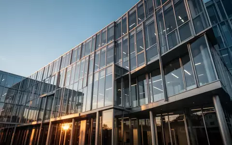 Moderne Glas- und Stahlfassade eines Bürogebäudes in der Schweiz bei goldenem Licht. - Foto: über boerse-global.de