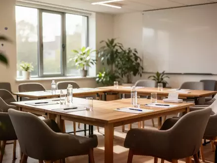 Ein heller, freundlicher Seminarraum mit leeren Tischen und Stühlen, vorbereitet für eine Schulung. - Foto: über boerse-global.de