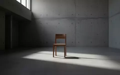 Ein minimalistischer, leerer Raum mit einem einzelnen Holzstuhl und langen Schatten bei natürlichem Lichteinfall. - Foto: über boerse-global.de