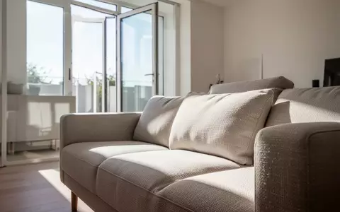 Ein helles, modern eingerichtetes Wohnzimmer mit Fokus auf die Textur eines Polstersofas bei natürlichem Lichteinfall. - Foto: über boerse-global.de