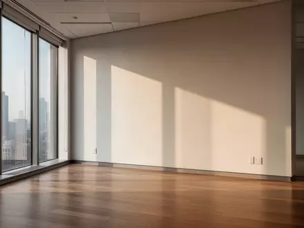 Ein minimalistischer, leerer Büroraum mit hellem, natürlichem Lichteinfall durch große Fenster auf einen Holzboden. - Foto: über boerse-global.de