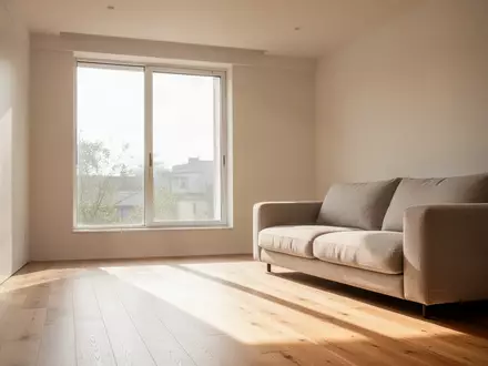 Ein helles, minimalistisch eingerichtetes Wohnzimmer mit natürlichem Lichteinfall und einem neutralen Sofa. - Foto: über boerse-global.de