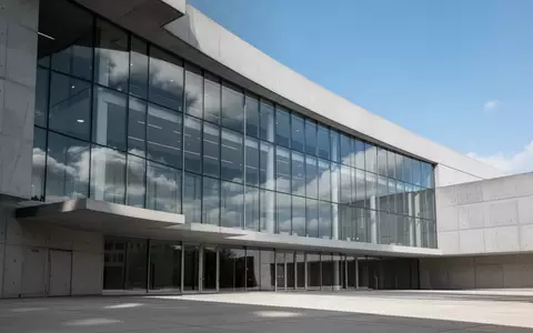 Moderne Fassade eines öffentlichen Gebäudes mit Glas und Beton bei klarem Himmel. - Foto: über boerse-global.de