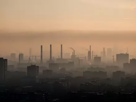 Dunstige, durch Feinstaub verschleierte Skyline einer Großstadt bei Sonnenaufgang mit sichtbarer Luftverschmutzung. - Foto: über boerse-global.de