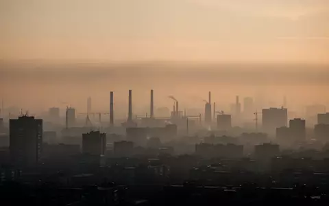 Dunstige, durch Feinstaub verschleierte Skyline einer Großstadt bei Sonnenaufgang mit sichtbarer Luftverschmutzung. - Foto: über boerse-global.de