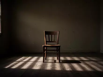Ein leerer Stuhl in einem schummrigen, kahlen Raum mit einfallendem Licht, das Schatten an die Wand wirft. - Foto: über boerse-global.de