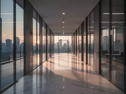 Ein minimalistischer, leerer Büroflur in einem modernen Gebäude bei Dämmerung mit langen Schatten und spiegelnden Böden. - Foto: über boerse-global.de