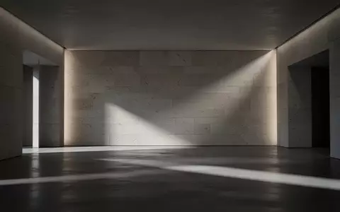 Eine leere, von dramatischem Licht beleuchtete Steinwand in einem modernen, minimalistischen Innenraum. - Foto: über boerse-global.de