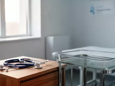 Ein steriler, modern eingerichteter medizinischer Untersuchungsraum mit einem Stethoskop auf einem Holztisch. - Foto: über boerse-global.de