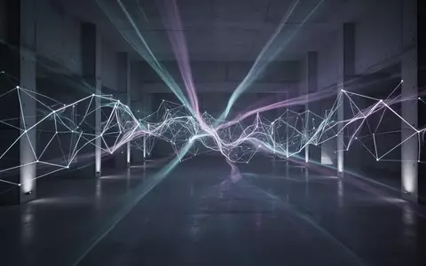 Abstrakte, leuchtende neuronale Netzwerkmuster in einer dunklen, minimalistischen Architekturhalle. - Foto: über boerse-global.de