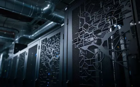 Nahaufnahme der metallischen Lüftungsgitter eines industriellen Serverschranks in einem dunklen Raum. - Foto: über boerse-global.de
