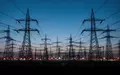 Hochspannungsmasten und industrielle Infrastruktur in einer weitläufigen Landschaft bei Dämmerung. - Foto: über boerse-global.de