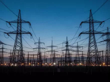 Hochspannungsmasten und industrielle Infrastruktur in einer weitläufigen Landschaft bei Dämmerung. - Foto: über boerse-global.de