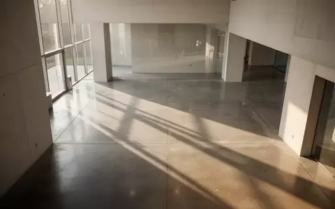 Minimalistisches, modernes Architekturinterieur mit klaren Linien und natürlichem Licht, das Schatten auf einen Betonboden wirft. - Foto: über boerse-global.de