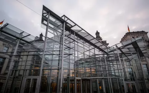 Moderne Glas- und Stahlfassade des Berliner Reichstagsgebäudes vor einem bewölkten Himmel. - Foto: über boerse-global.de