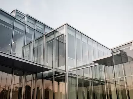 Moderne Architektur aus Glas und Stahl bei Tageslicht, die die Stabilität und Transparenz im Finanzsektor symbolisiert. - Foto: über boerse-global.de