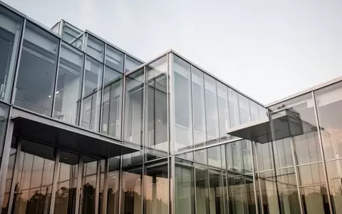 Moderne Architektur aus Glas und Stahl bei Tageslicht, die die Stabilität und Transparenz im Finanzsektor symbolisiert. - Foto: über boerse-global.de