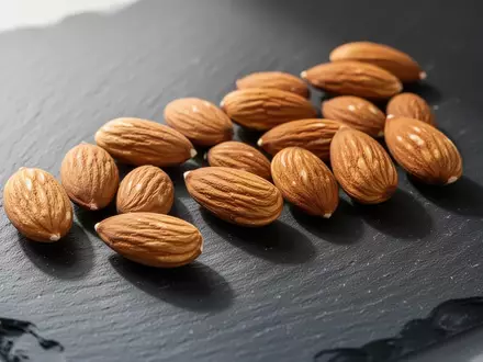 Frische Mandeln auf einer dunklen Schieferplatte als Symbol für gesundheitsbewusste Ernährung zur Blutzuckerregulierung. - Foto: über boerse-global.de