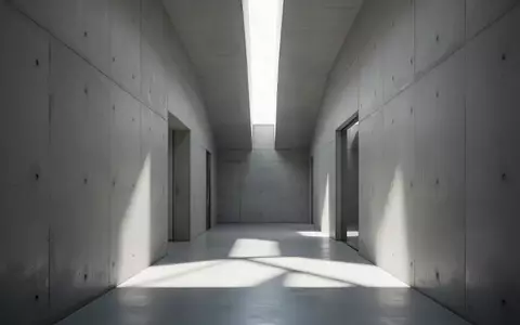 Ein minimalistischer, moderner Flur mit klaren Betonwänden und diffusem Tageslicht, das geometrische Schatten wirft. - Foto: über boerse-global.de