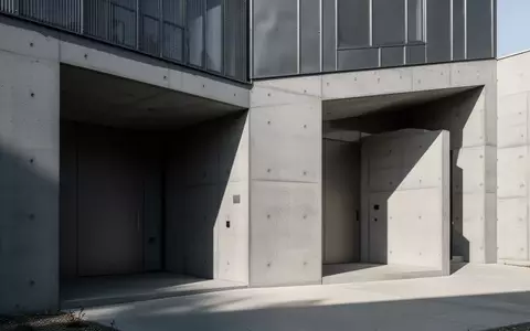 Moderne Gebäudefassade mit minimalistischen Eingängen aus Beton und Metall bei Tageslicht. - Foto: über boerse-global.de