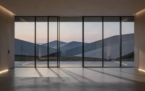 Ein minimalistisch gestalteter Innenraum mit bodentiefen Fenstern und Blick auf eine abstrakte Landschaft bei Dämmerung. - Foto: über boerse-global.de
