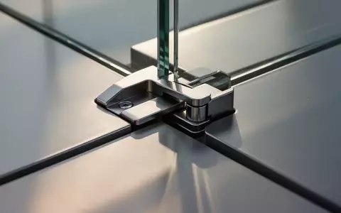 Ein technisches Scharnier aus gebürstetem Metall, das in eine Glasoberfläche eingelassen ist. - Foto: über boerse-global.de