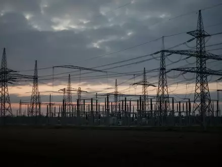 Eine weitläufige Hochspannungs-Umspannanlage in der Dämmerung unter einem bewölkten Himmel. - Foto: über boerse-global.de