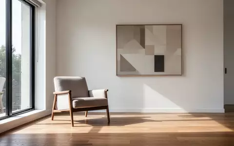 Ein minimalistisch eingerichteter, sonnendurchfluteter Wohnbereich mit einem Sessel vor einem Fenster. - Foto: über boerse-global.de